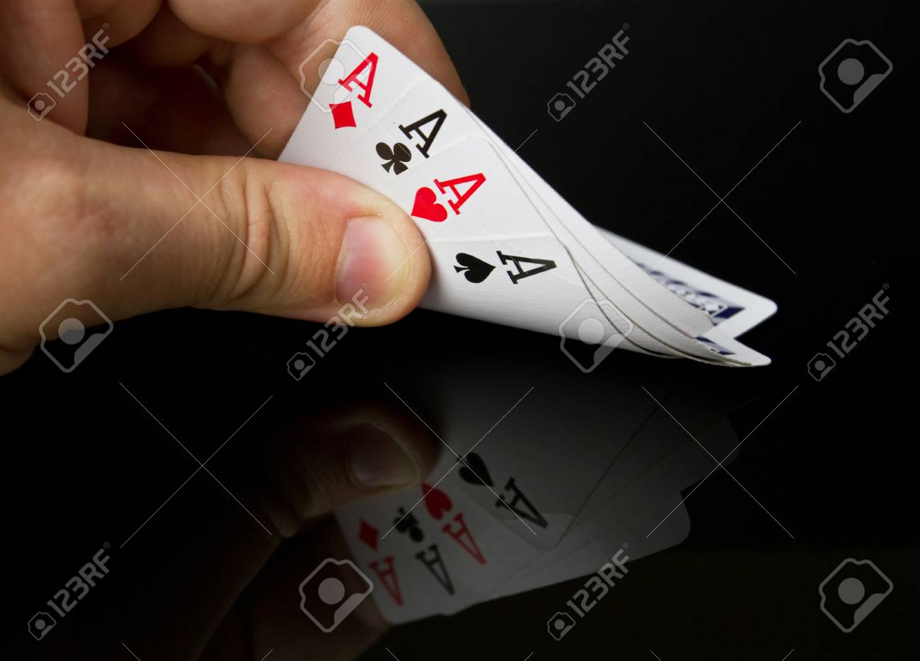 56498113-hand-holding-four-aces-with-reflection-on-table.jpg